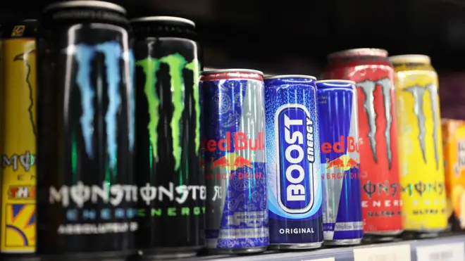 Close of of differnet energy drink brands lined up on a shelf in a supermarket