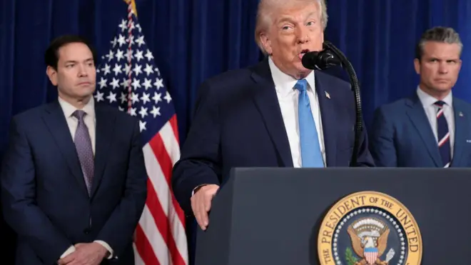 Presidente dos EUA, Donald Trump, em coletiva de imprensa enquanto o secretário de Defesa, Pete Hegseth, e o secretário de Estado, Marco Rubio, observam.
