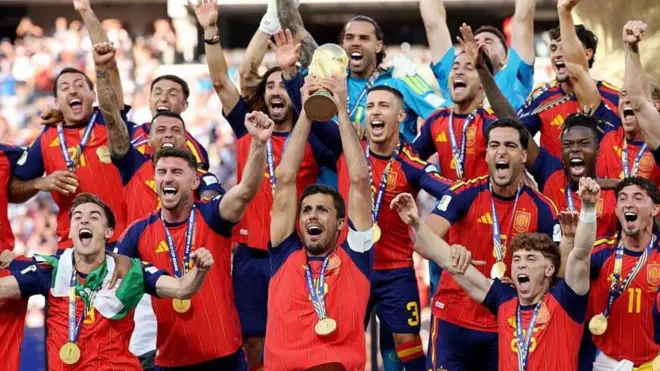 لاعبو منتخب إسبانيا بالقميص الأحمر والكحلي يرتدون ميداليات ذهبية ويحملون كأس العالم