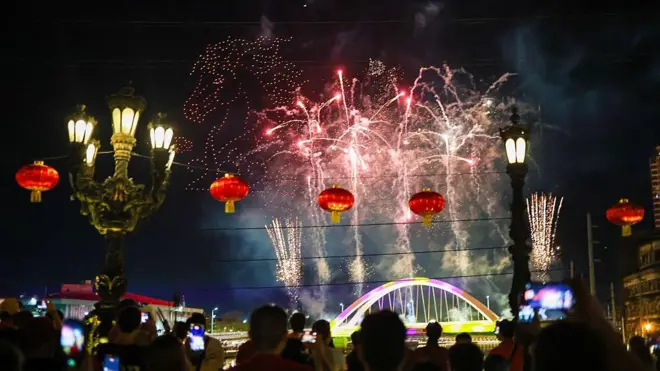 Дроны на небе образуют изображение лошади, а снизу взлетают фейерверки.