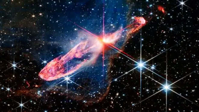 A red star in the process of forming against a field of stars.