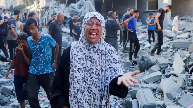 Umugore urimo kurira nyuma y'igitero cya nijoro cya Israel cyo mu kirere ku nzu yo mu mujyi wa Gaza, mu majyaruguru ya Gaza. Inyuma ye hari abandi bantu benshi biganjemo abagabo. Ifoto yo ku itariki ya 16 Nzeri (9) mu mwaka wa 2025. 