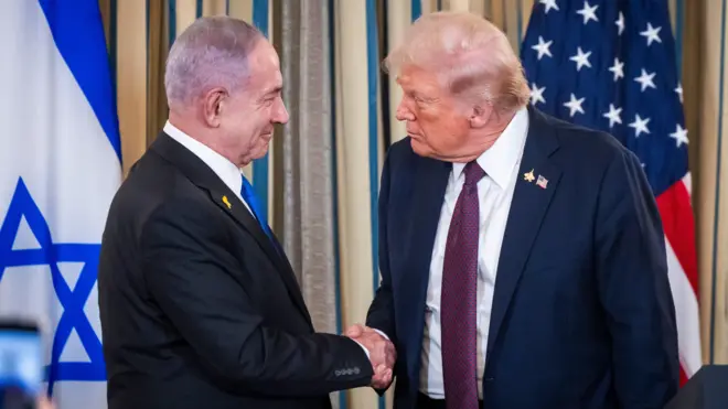 Benjamin Netanyahu stands in front of Israel's flag as he shakes Donald Trump's hand. Trump stands in front of the US flag.