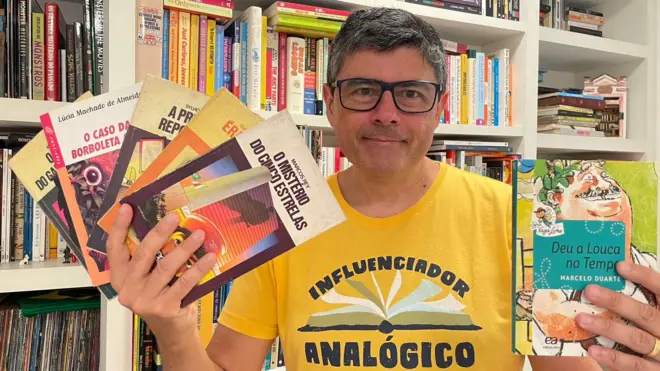 O escritor Marcelo Duarte segura livros da série Vaga-Lume