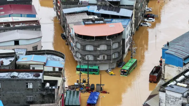 中國南寧橫州市，從無人機航拍所見洪水淹沒住宅等建築，汽車以至於巴士（公交車）也被浸泡水中。（中新社圖片6/7/2026）