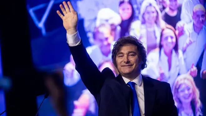 Javier Milei saluda a sus seguidores en un evento en la noche. 