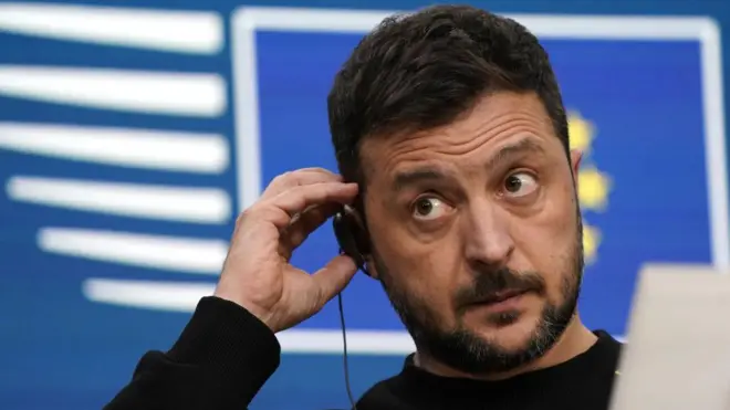 Зеленський прислухається до навушника з перекладом