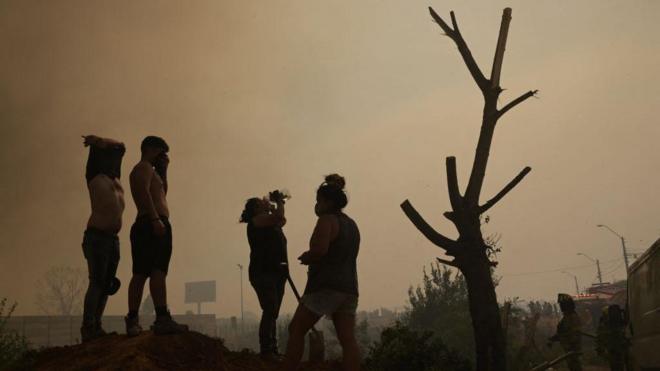 Los residentes ayudan a los bomberos durante un incendio forestal en los cerros de Quilpué, en Viña del Mar.