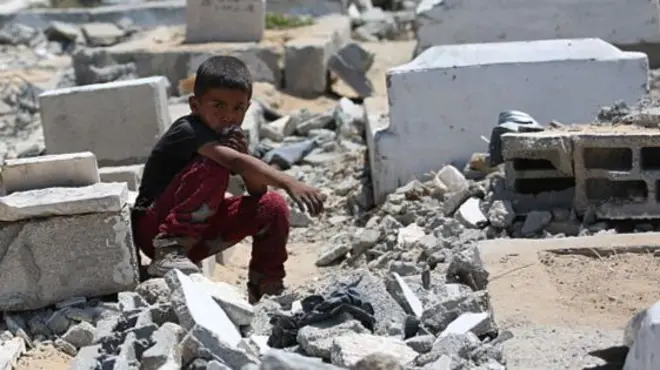 Palestinians, including children inspect the site after an Israeli airstrike severely damaged the Al-Ansar Mosque and partially destroyed the surrounding cemetery in Deir al-Balah, located in the central Gaza Strip on June 03, 2025