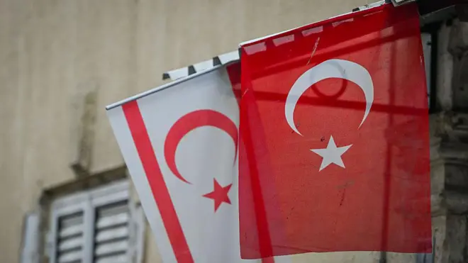 Bir sokakta Türkiye ve Kıbrıs Türk tarafı bayrağı yan yana sallanıyor.