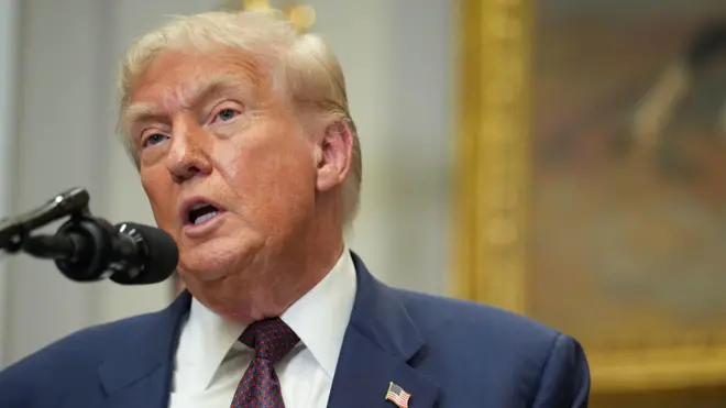 Donald Tramp ispred mikrofona u odelu (bela košulja, crveno plava kravata i plavi sako)