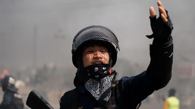 नेपाल में शुक्रवार को हिंसा के दौरान भीड़ का काबू करने का निर्देश देता सुरक्षाकर्मी