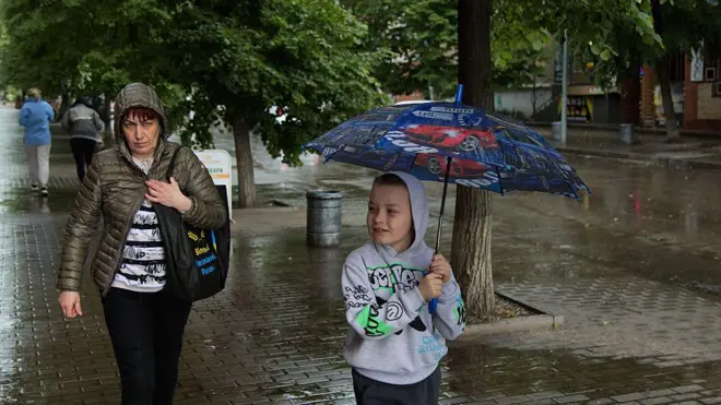 жінка та хлопчик ідуть під дощем у місті