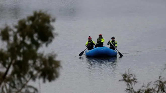 Equipes de resgate remam em um barco inflável enquanto realizam buscas ao longo de um curso d'água após uma enchente repentina em Kerrville, no Texas