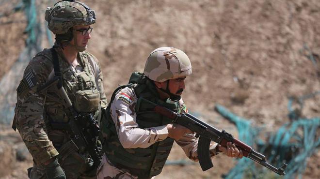 ضابط أمريكي يرقب مجندا عراقيا أثناء تدريبات أجرتها القوات الأمريكية للجيش العراقي في قضاء التاجي عام 2015