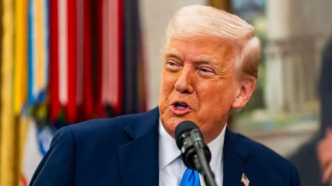 Trump on blue tie speaking to a mic