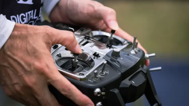 Dłonie mężczyzny trzymają urządzenie do kontroli drona