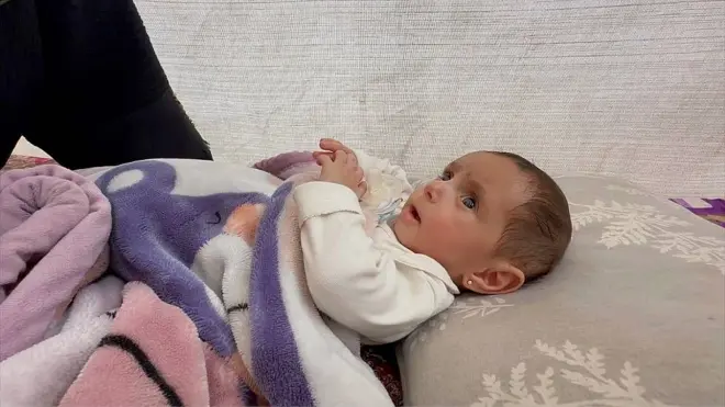 Niveen mirando a su madre mientras está sobre una almohada