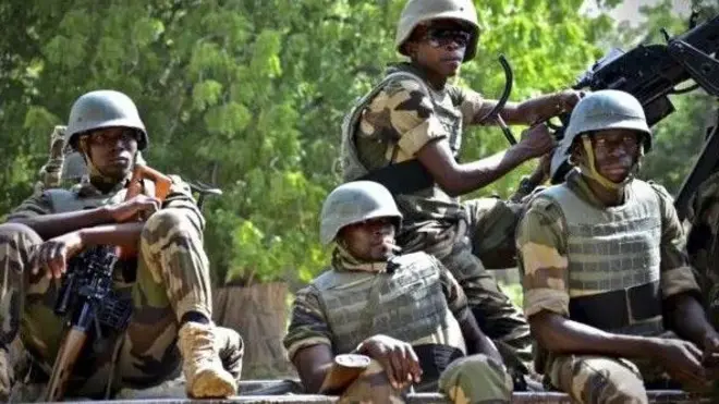 Awọn ọmọ ologun to wa ninu asọ khaki wọn de ate sori, wọ ẹwu ayẹta, wọn si gbe ibọn lọwọ, gbogbo wọn joko sori ọkọ ijagun