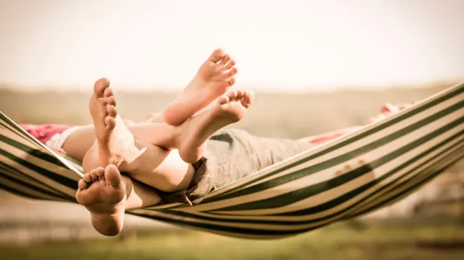 Los pies de una madre y una hija en una hamaca