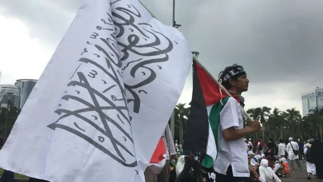 Seorang pria membawa bendera Palestina dalam Aksi Bela Palestina di Monas, Jakarta Pusat, Minggu (17/12)