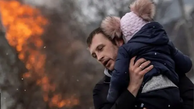 Ọkunrin kan gbe ọmọ kekere kan si ejika