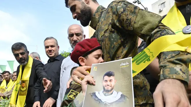 مقاتل من حزب الله يواسي ويحتضن نجل فضل عباس بزي أثناء تشييع جنازة والده الذي لقى مصرعه في انفجارات أجهزة الاتصالات اللاسلكية.