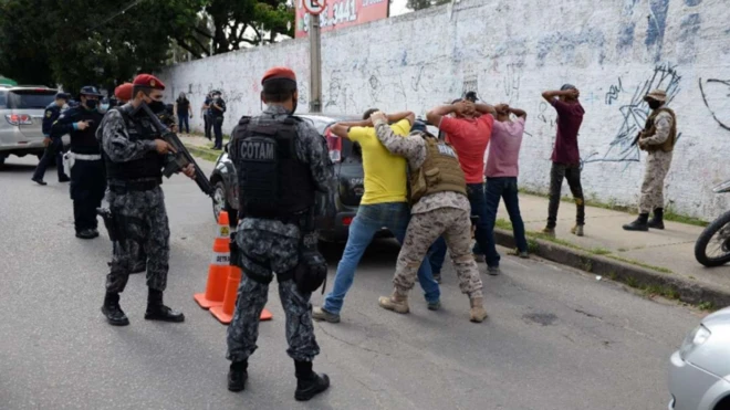 Policiais revistam pessoas na rua 