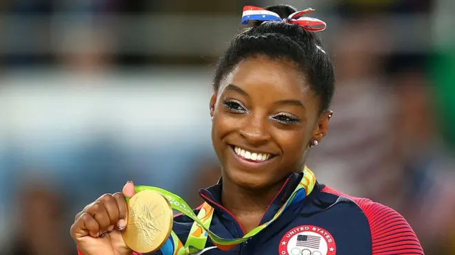 Simone Biles holds up one of the four gold medals she won at the 2016 Rio Olympics