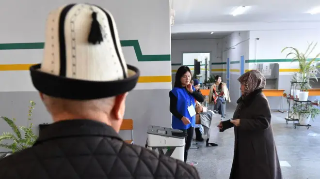 Бабушка несет бюллетень, чтобы положить в урну