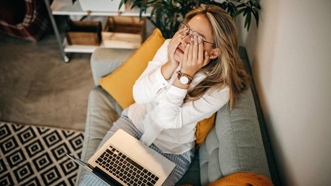 Mulher cansada trabalhando com laptop no colo no sofácasino 1 euro depositcasa