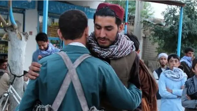 A militant hugs a member of the Afghan police in Kunduz