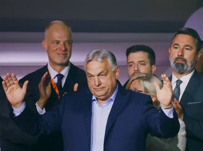 Viktor Orban con los brazos abiertos. Tras él hay un grupo de cuatro personas. 
