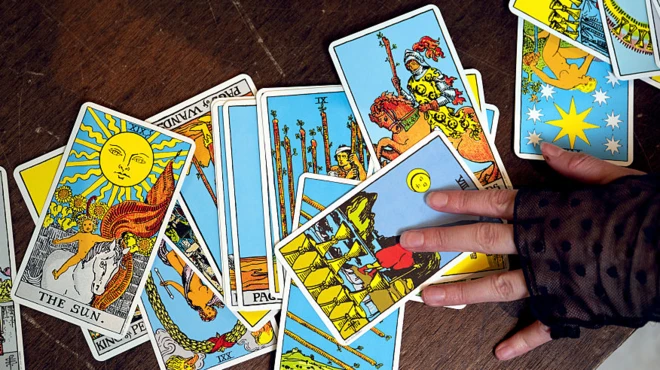 Карты таро раскладывает на столе женская рука
