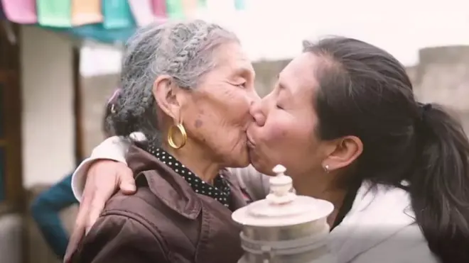 పెద్దావిడను ముద్దాడుతున్న యువతి