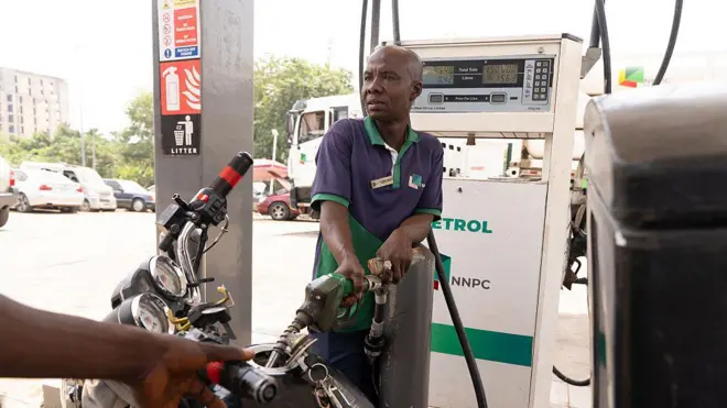 Foto of fuel attendant as e dey pump petrol into one motorcycle for fuel station for Abuja