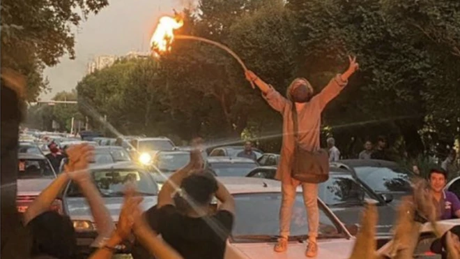 عکس دختری بالای یک خودرو با مشعلی در دست