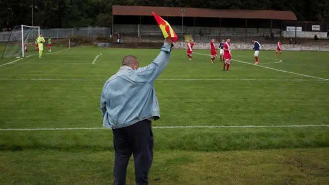Pomoćni sudija na Milbrun Parku, u Aleksandriji, nakon što je fudbalski klub Vel of Leven ( u plavom) ugostio Ašfild iz Škotske vest lige 2016. godine. Vel od Leven bio je jedan od osnivača Škotske lige 1890. godine i ostao deo SFA do 1929. godine. Posle Drugog svetskog rata klub je ponovo osnovan, kada postaje član Škotske juniorske fudbalske asocijacije. Meč su izgubili od Ašfilda 4:3.