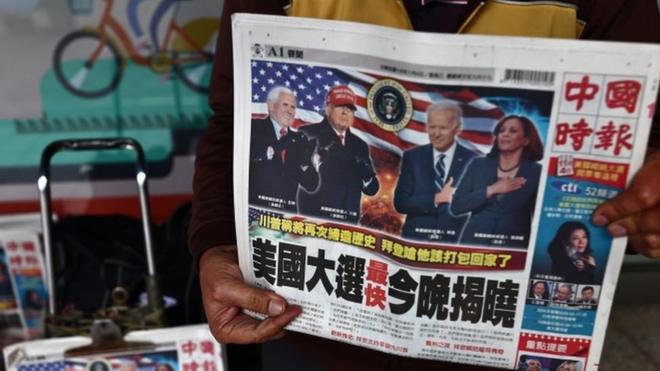 A man sells newspapers with front page articles about the US election along a street in Taipei