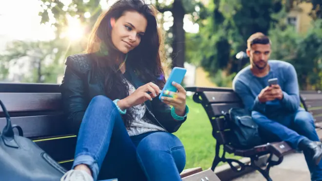 Elinde telefonlarıyla bir kadın ve bir erkek