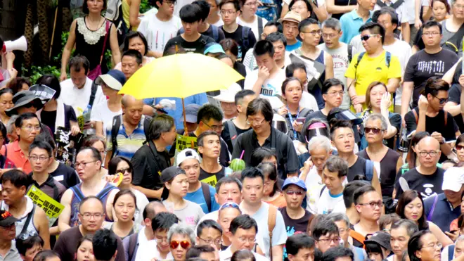 香港七一游行队列中一名示威者举起黄色雨伞（1/7/2017）