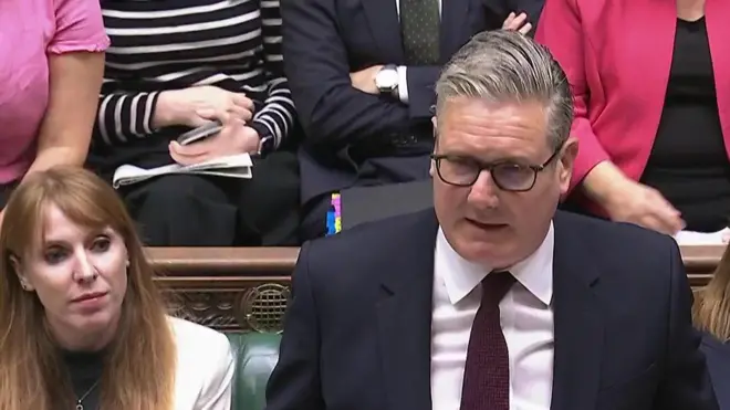 下院で首相質問に臨むダークスーツ姿のスターマー首相を後ろの閣僚席から見ている レイナー氏。白い上着を着ている