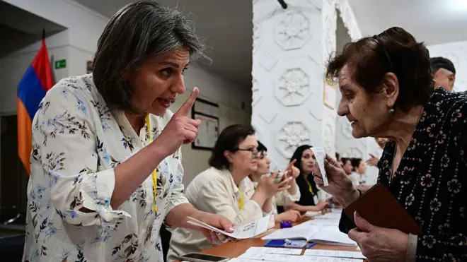 Bir sandık görevlisi, yaşlı bir kadına nasıl oy kullanacağını anlatıyor
