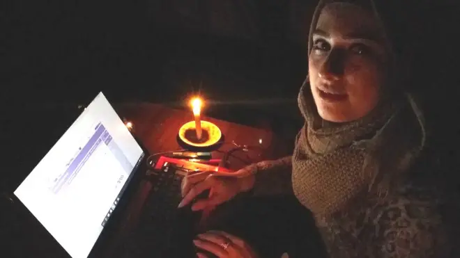 મીણબતીના અજવાળા હેઠળ ભણતી એક યુવતી