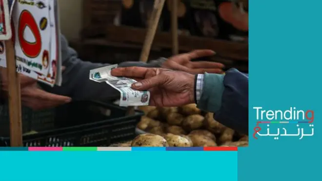 صورة لشخص يشتري خضروات ويحمل ورقة نقدية فئة 100 جنيه مصري