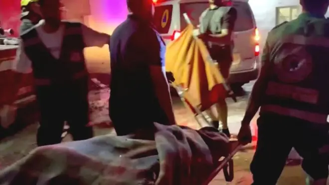 Rescue workers carry a victim of the explosion at Gaza City's Al-Ahli Arab hospital (17 October 2023)