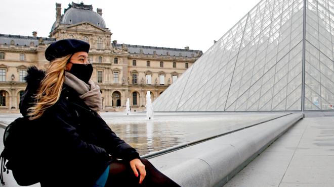 mulher de máscara em frente ao louvre em paris