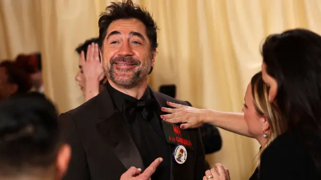 الممثل الإسباني خافيير بارديم يرتدي دبوساً كتب عليه "فلسطين" وشعاراً مناهضاً للحرب على السجادة الحمراء خلال وصول الضيوف إلى حفل توزيع جوائز الأوسكار في دورته الـ98 في هوليوود، لوس أنجلوس، الولايات المتحدة، 15 مارس/آذار 2026 