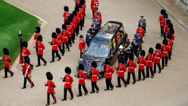 The hearse carrying the Queen is covered with flowers that were thrown by well-wishers on the way to Windsor