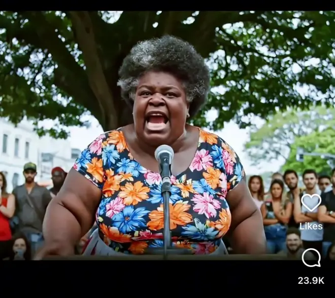 Avatar de inteligência artificial representa uma mulher idosa negra que grita em um microfone, com público ao fundo